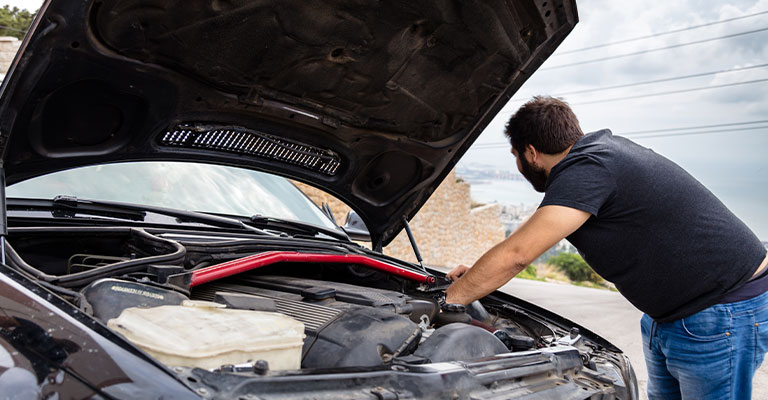 Open the hood and locate the headlight adjustment screws on each side of the car